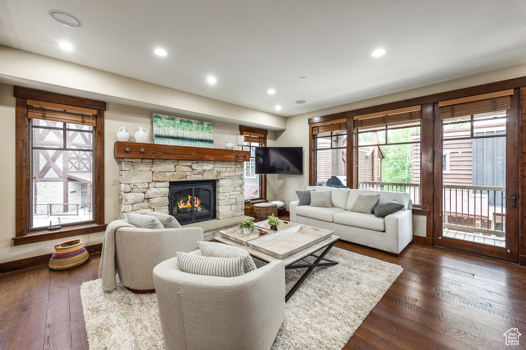 Living area with dark wood-type flooring, a stone fireplace, and recessed lighting