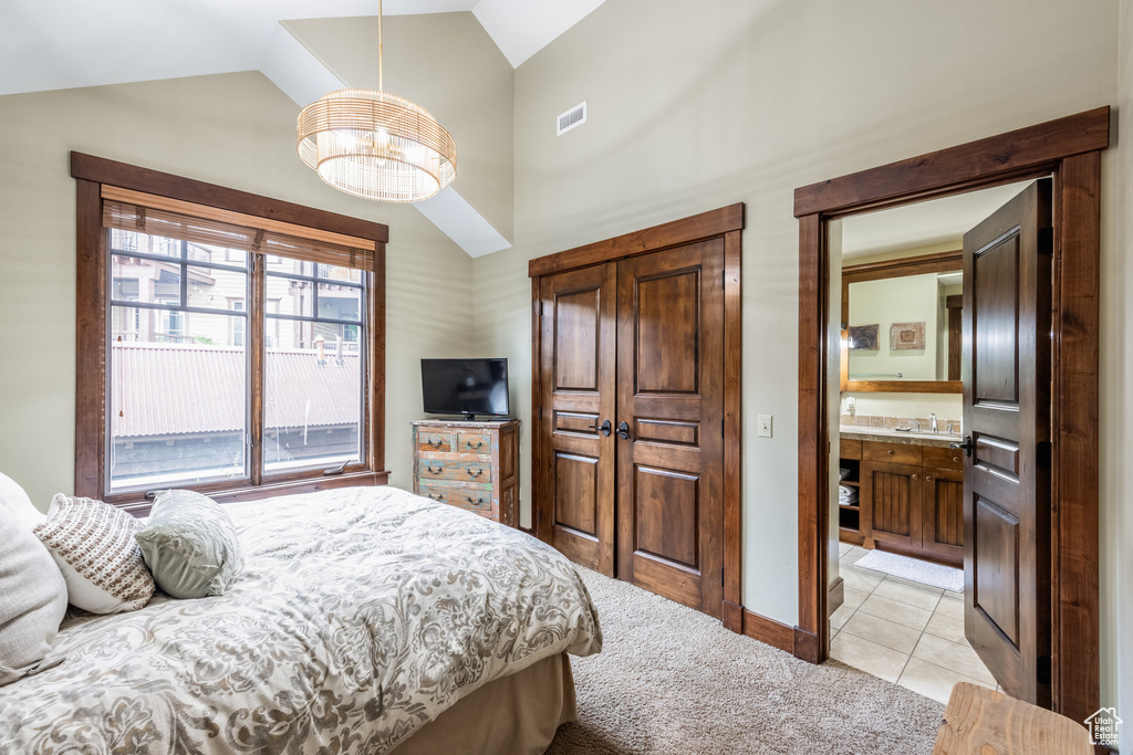 Bedroom with a chandelier, light tile patterned floors, light colored carpet, and high vaulted ceiling