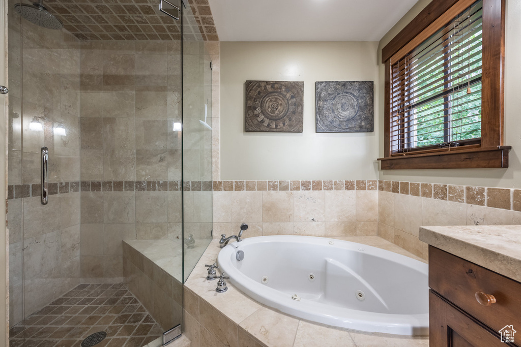 Full bath featuring a whirlpool tub, a stall shower, and vanity