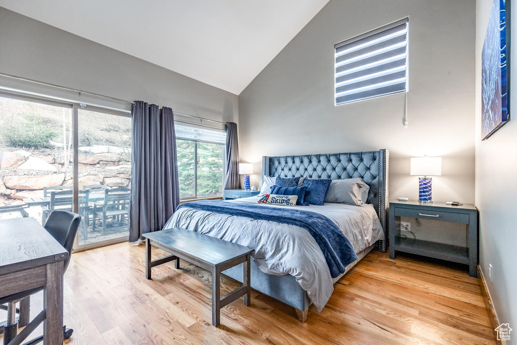 Bedroom featuring high vaulted ceiling, access to outside, and light wood-type flooring