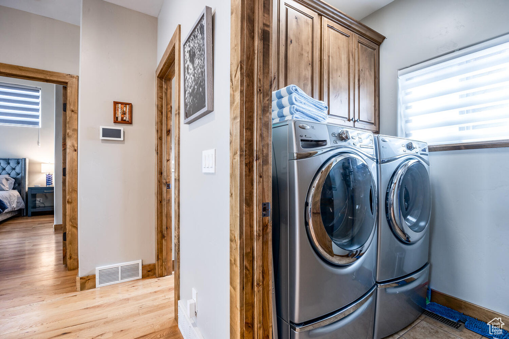 Laundry room featuring cabinet space, washing machine and dryer, and light wood finished floors