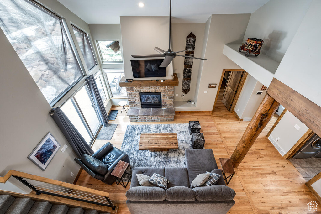 Living area with wood finished floors, a towering ceiling, a fireplace, a ceiling fan, and stairway