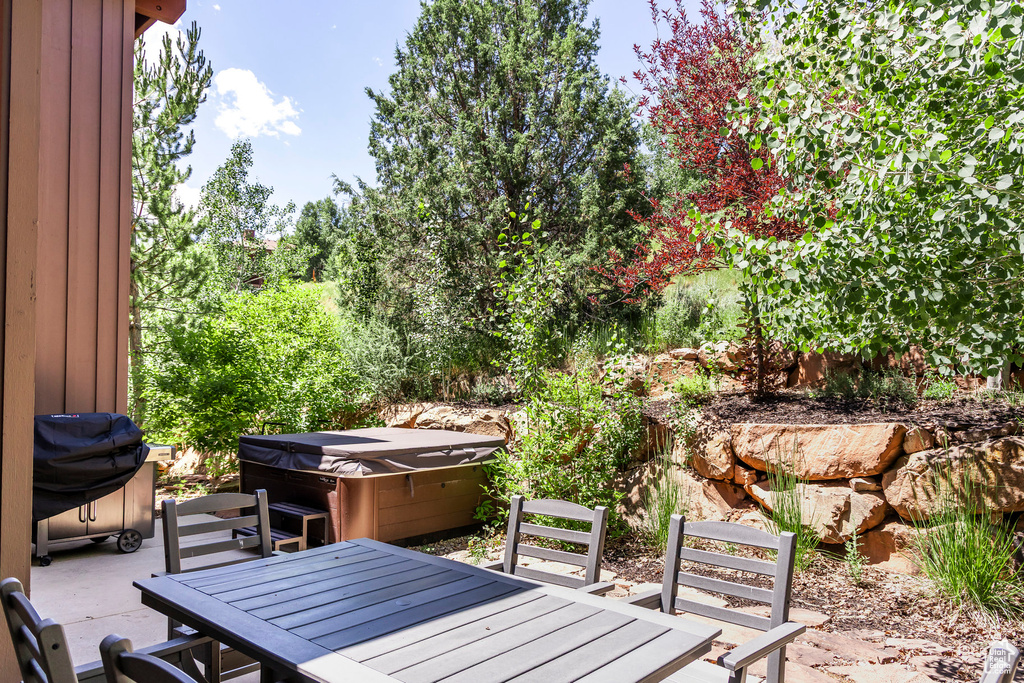 Deck featuring a hot tub, outdoor dining area, a patio, and area for grilling