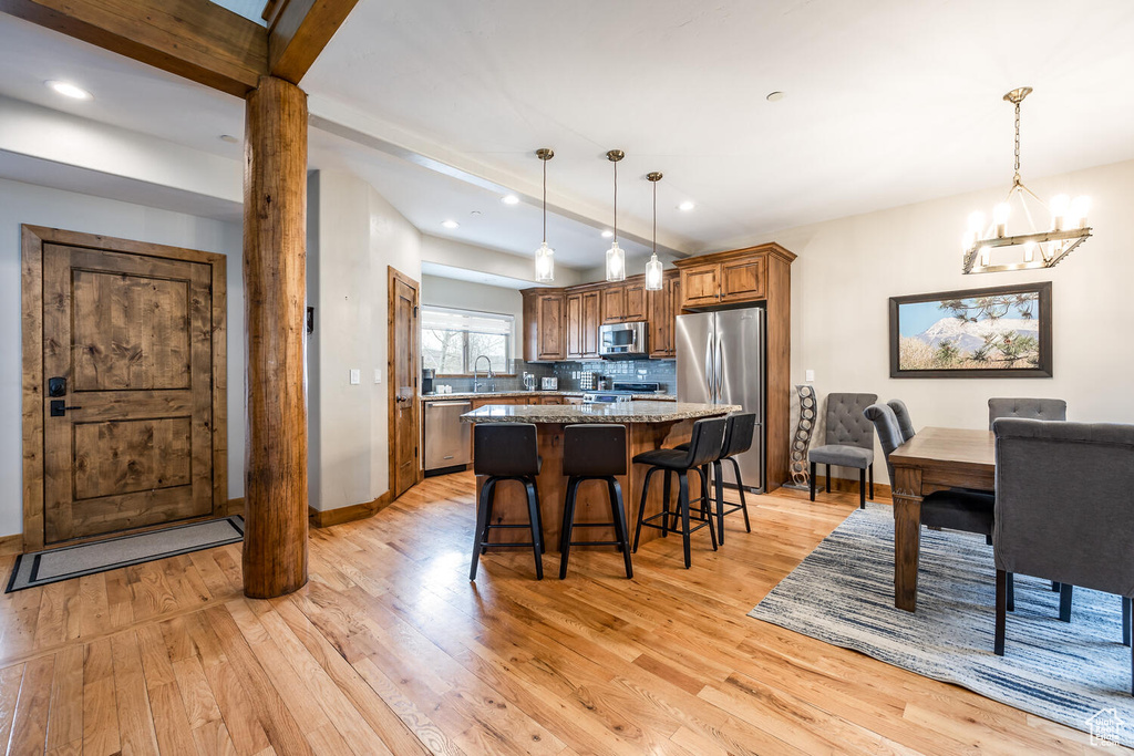 Kitchen with appliances with stainless steel finishes, light wood finished floors, a chandelier, backsplash, and recessed lighting