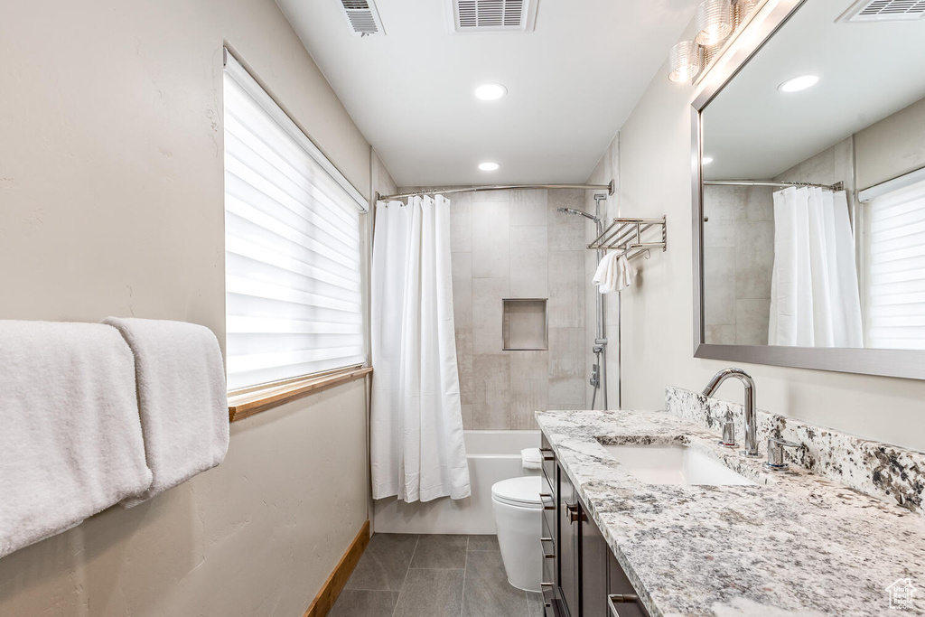 Bathroom featuring healthy amount of natural light, vanity, shower / tub combo, and recessed lighting
