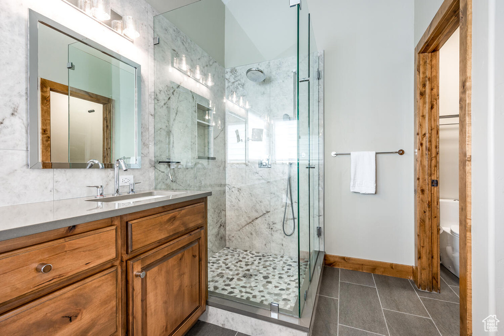 Full bathroom featuring vanity, a marble finish shower, and tile patterned floors