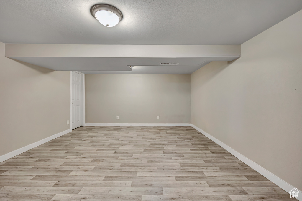 Finished below grade area with light wood-style flooring and baseboards