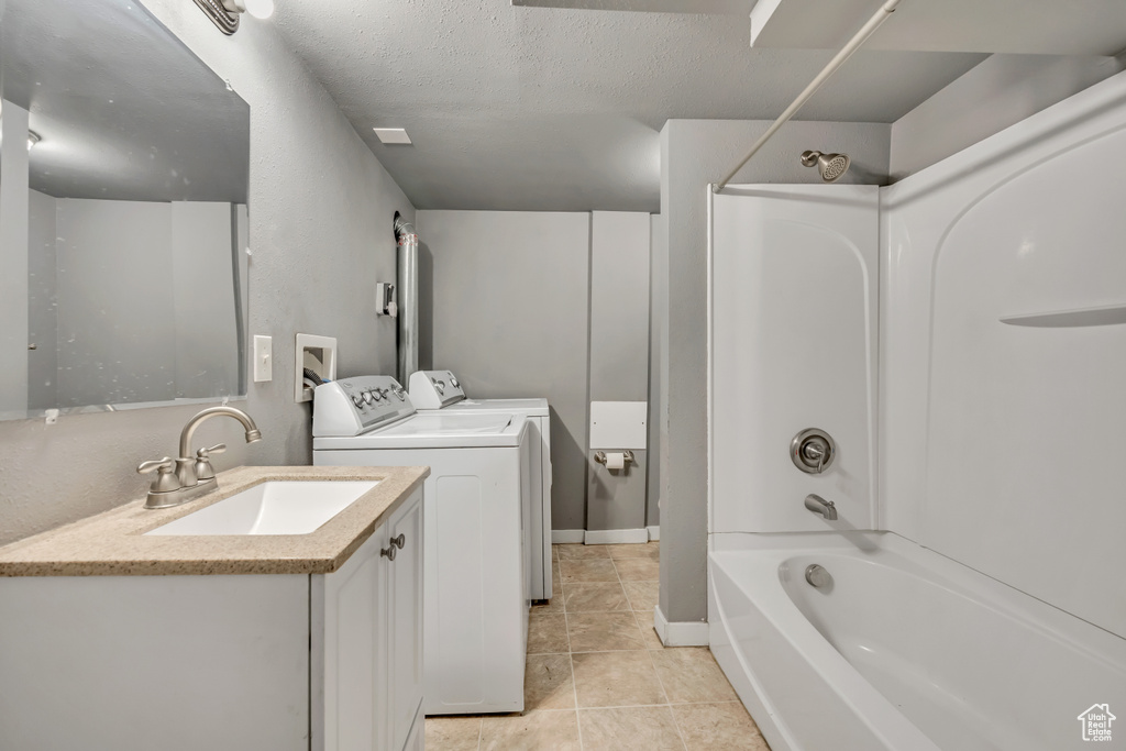 Bathroom with washing machine and clothes dryer, vanity, shower / washtub combination, tile patterned floors, and a textured ceiling