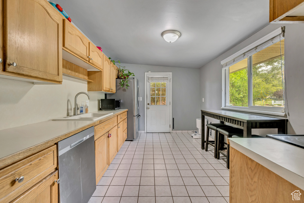 Kitchen with appliances with stainless steel finishes, light countertops, light tile patterned floors, and light brown cabinetry