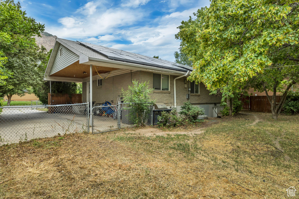 View of home's exterior with an attached carport, solar panels, and a gate
