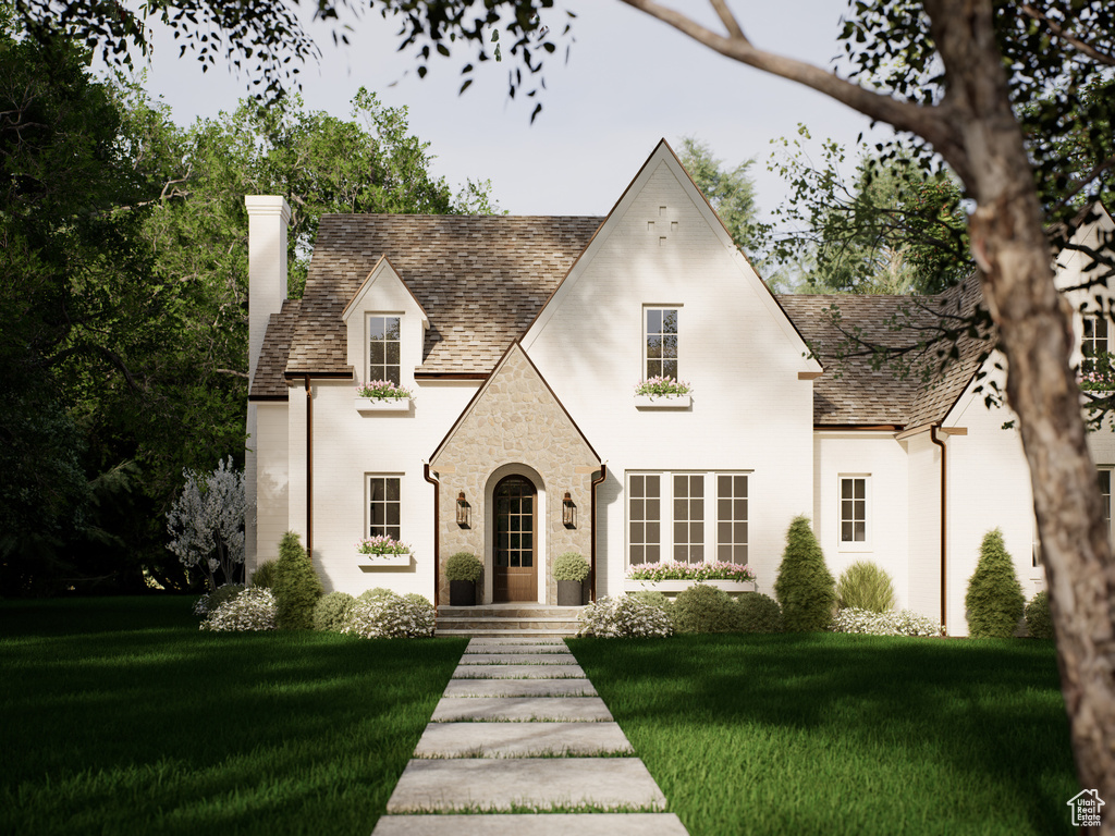 View of front facade featuring a chimney, a front yard, stone siding, and brick siding
