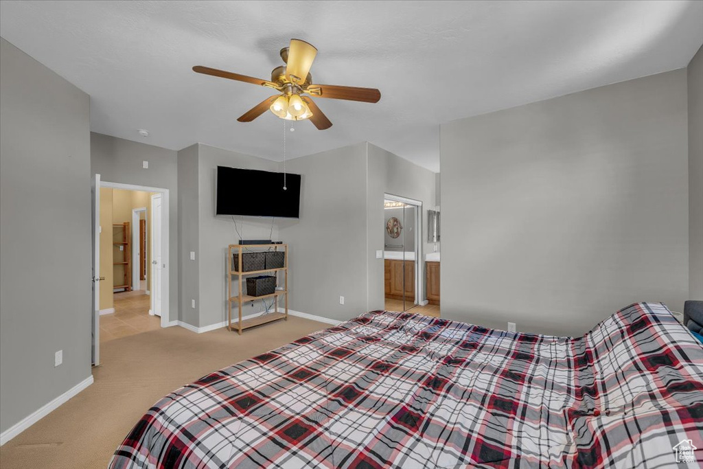 Bedroom featuring light colored carpet, a ceiling fan, and connected bathroom