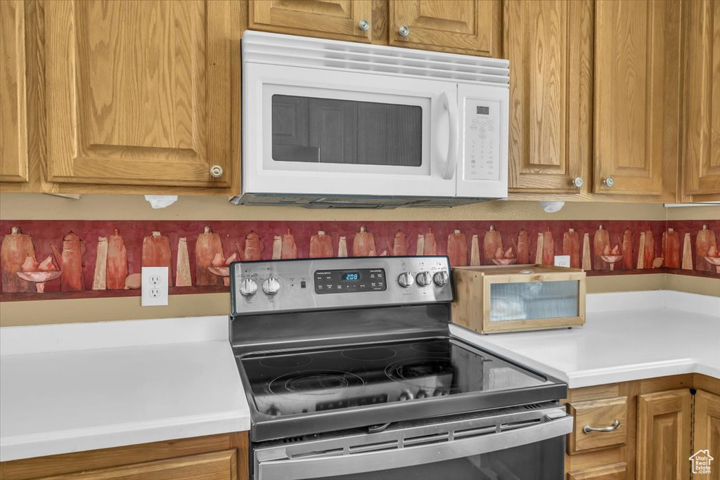 Kitchen featuring electric range, white microwave, and light countertops