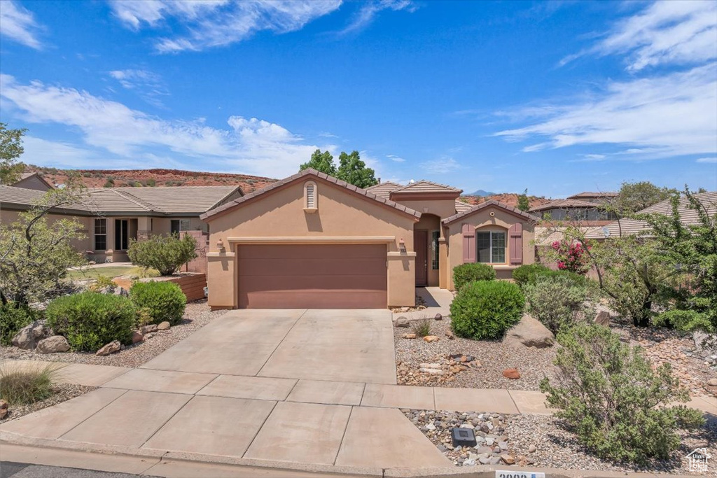 Mediterranean / spanish-style house with stucco siding, an attached garage, concrete driveway, and a tile roof