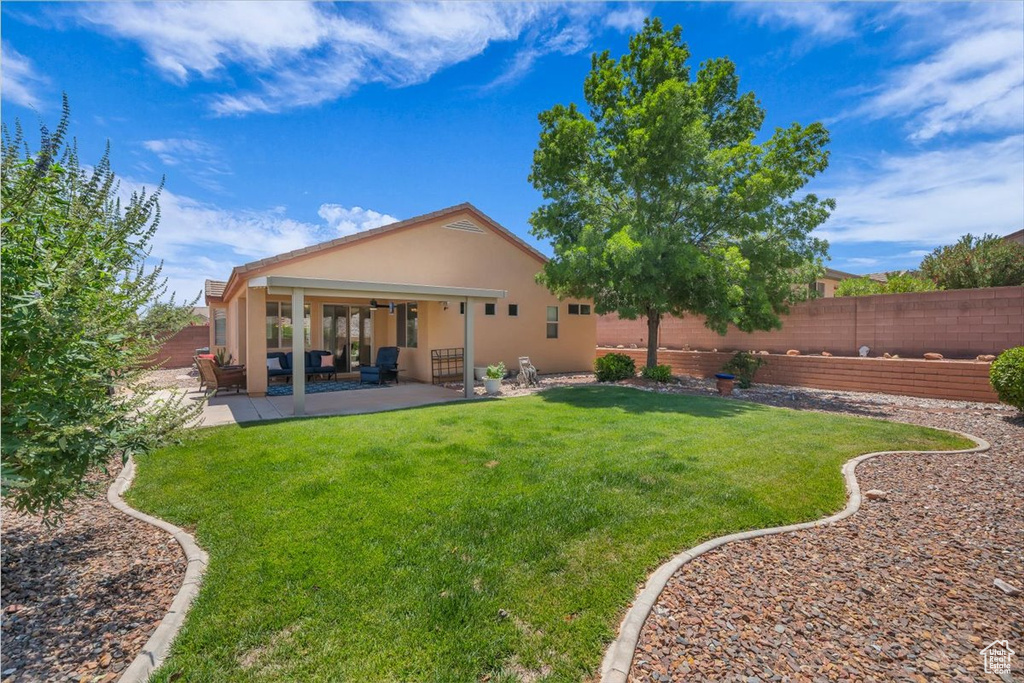 Back of property with ceiling fan, stucco siding, a patio area, a fenced backyard, and outdoor lounge area