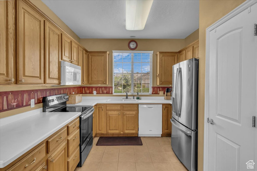 Kitchen with appliances with stainless steel finishes, light tile patterned floors, and light countertops