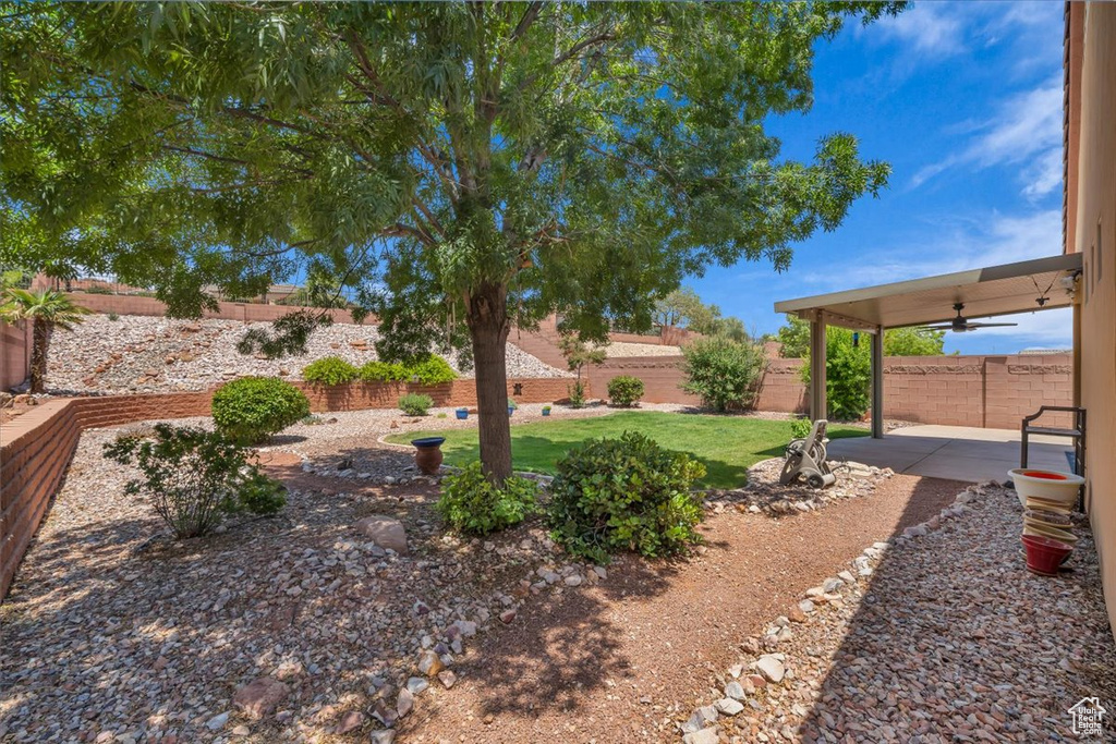 Fenced backyard with a ceiling fan and a patio
