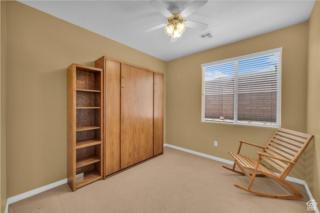 Living area featuring light colored carpet and ceiling fan