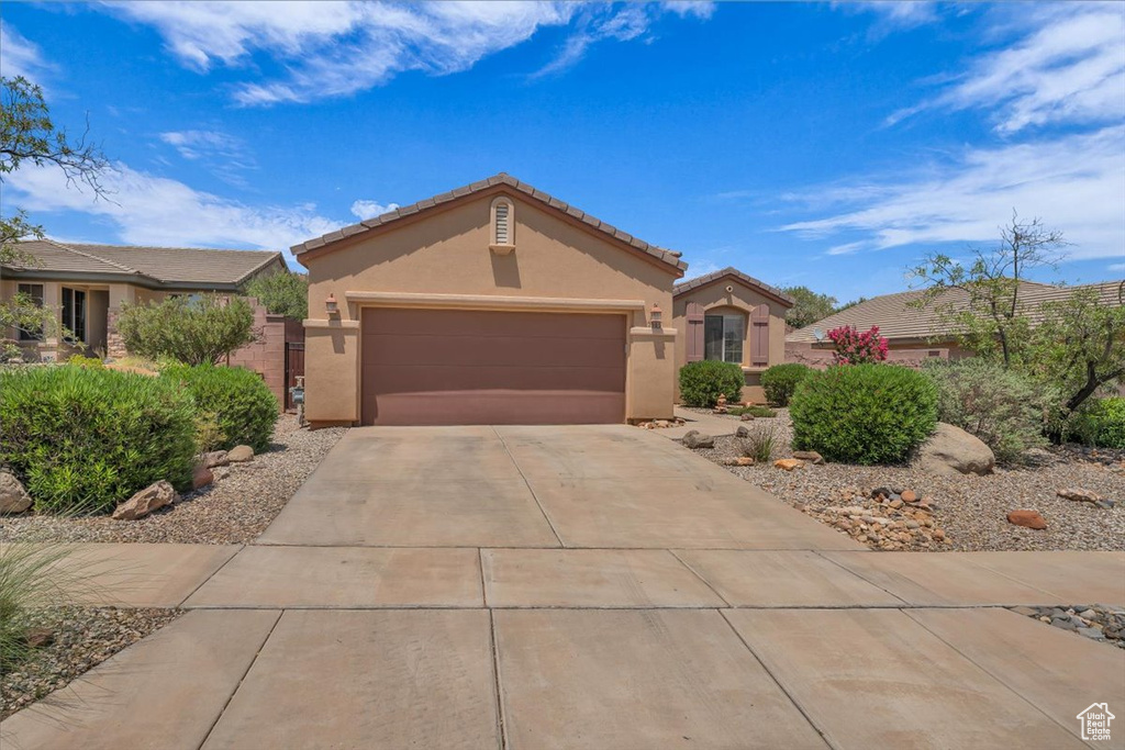View of front of home featuring stucco siding, an attached garage, concrete driveway, and a tiled roof