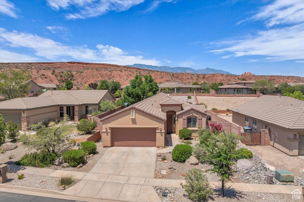 View of front of property with a garage, a mountain view, driveway, stucco siding, and a tiled roof