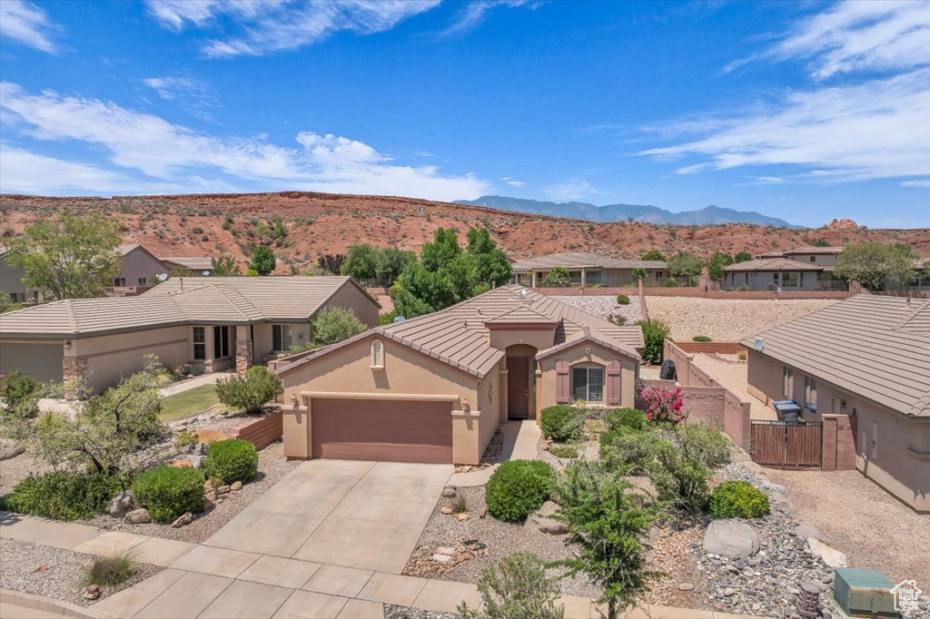 View of front of house featuring a garage, a gate, a mountain view, driveway, and stucco siding