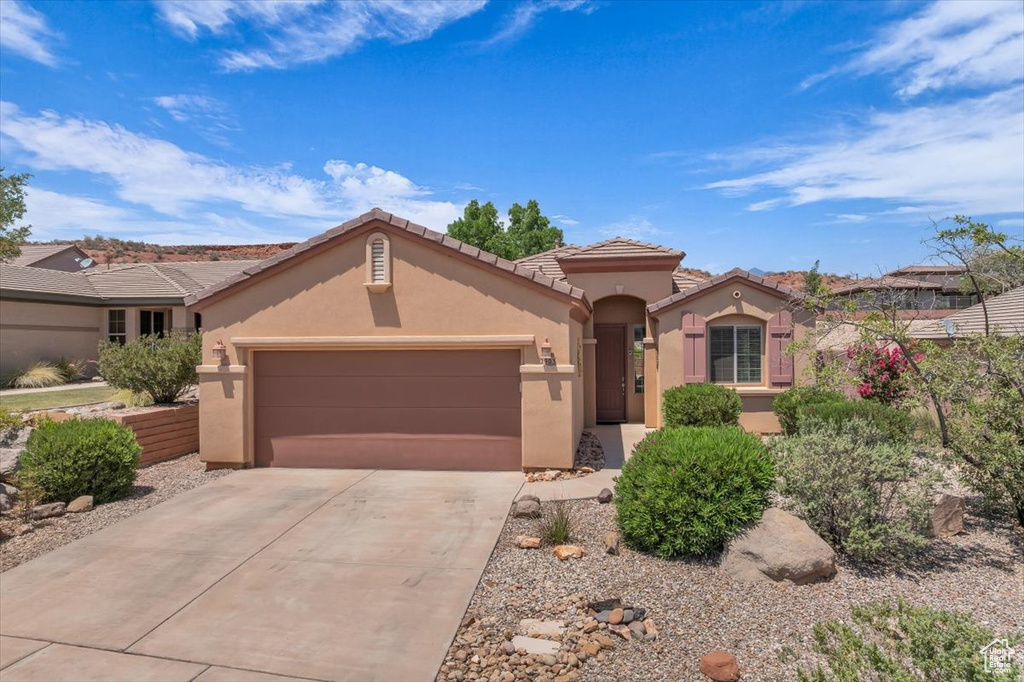 Mediterranean / spanish-style home with stucco siding, a garage, concrete driveway, and a tiled roof