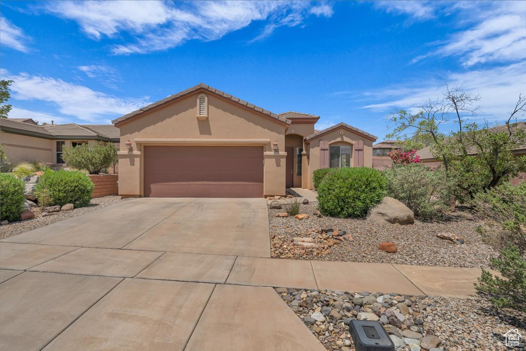 View of front of home with stucco siding, an attached garage, concrete driveway, and a tile roof