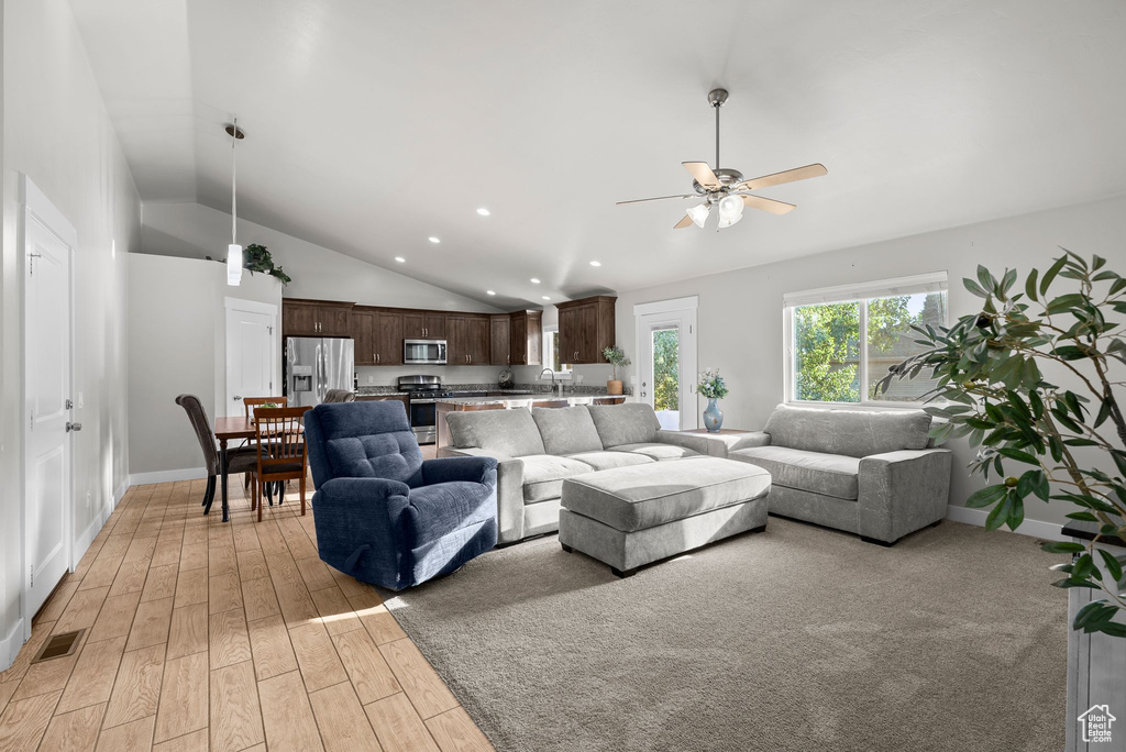 Living room featuring a ceiling fan, vaulted ceiling, light wood finished floors, and recessed lighting