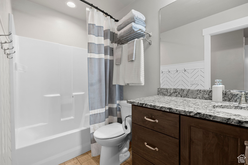 Full bath featuring vanity, shower / tub combo with curtain, and wood finished floors