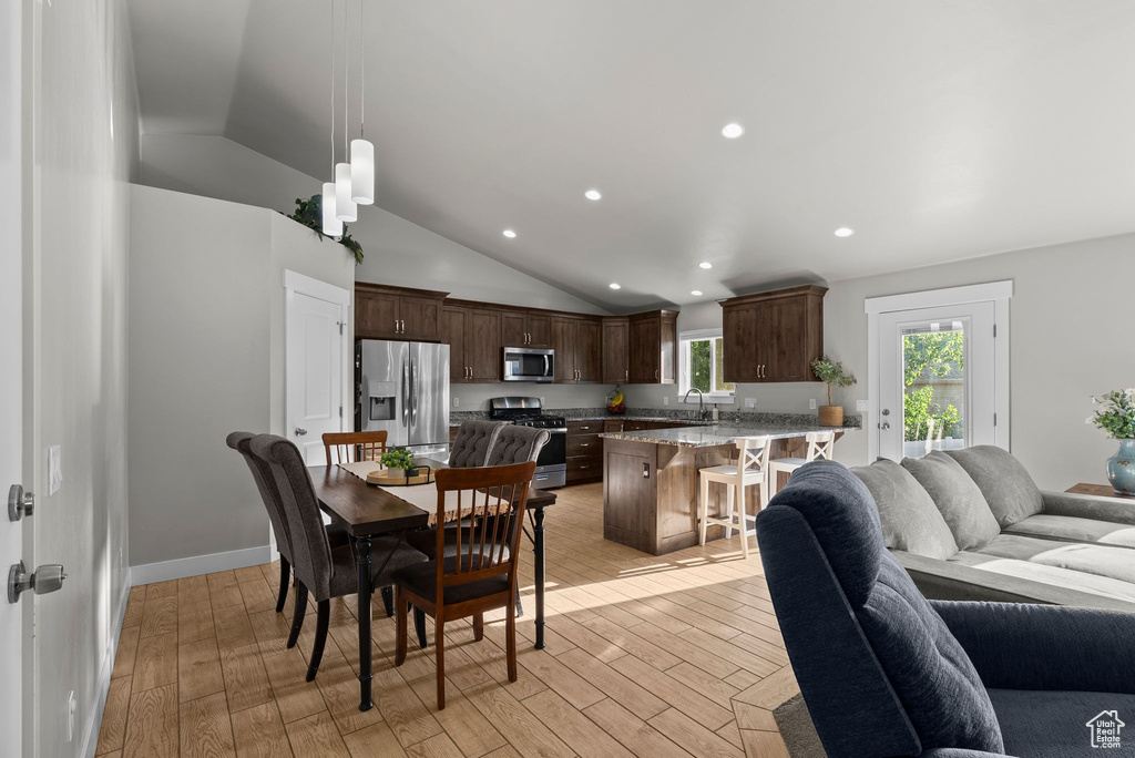 Dining area with vaulted ceiling, light wood-style floors, and recessed lighting