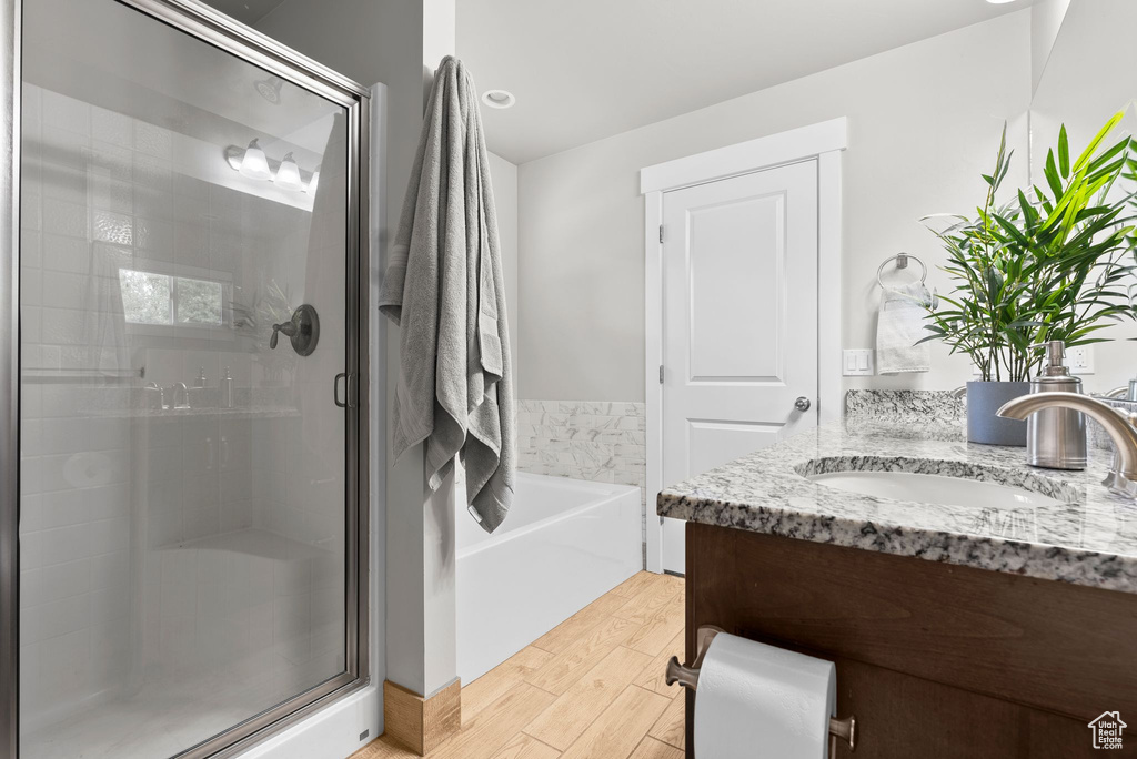 Bathroom with a shower stall, vanity, a bath, and wood finished floors