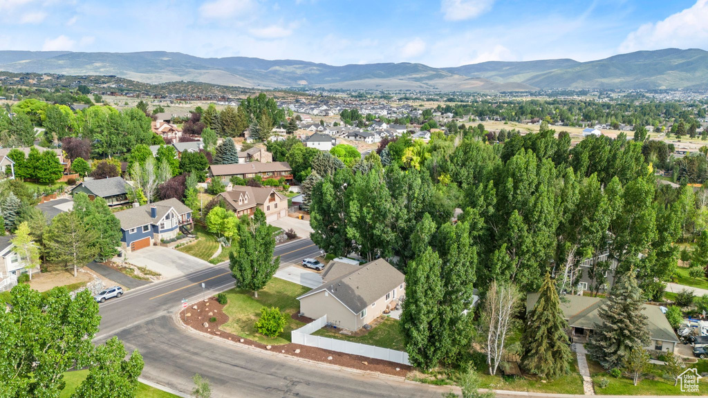 Aerial view of property and surrounding area featuring mountains and nearby suburban area