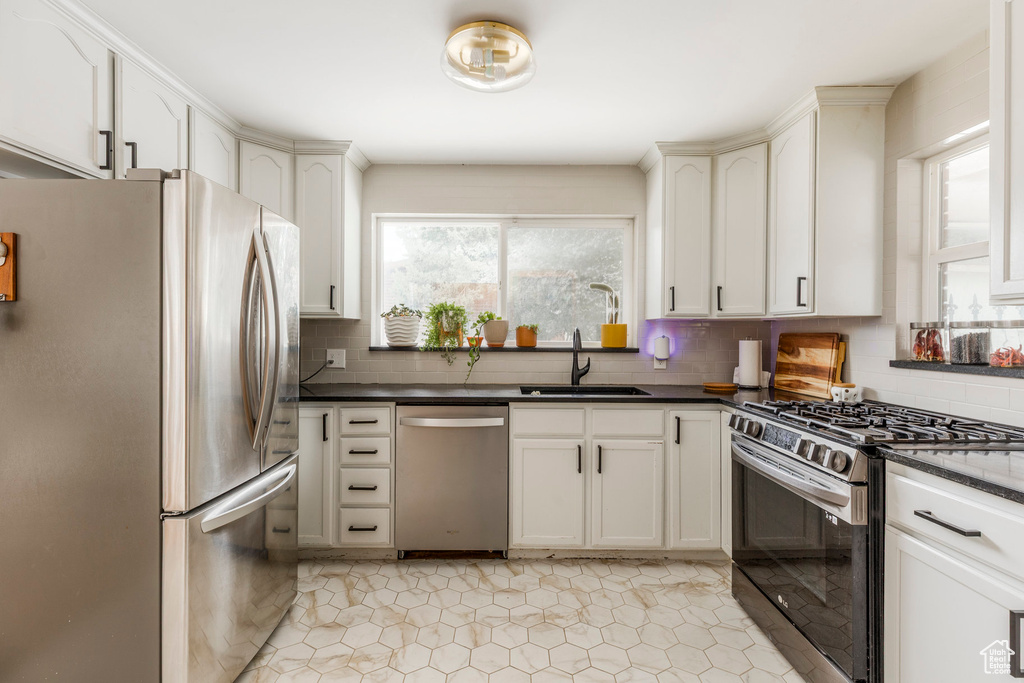 Kitchen featuring appliances with stainless steel finishes, dark countertops, tasteful backsplash, and light tile patterned floors