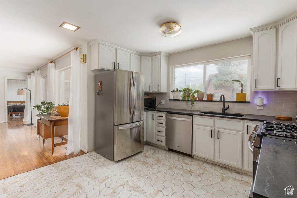Kitchen featuring stainless steel appliances, dark countertops, and decorative backsplash