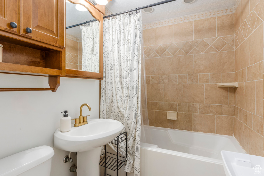 Full bathroom featuring shower / bath combo with shower curtain and toilet
