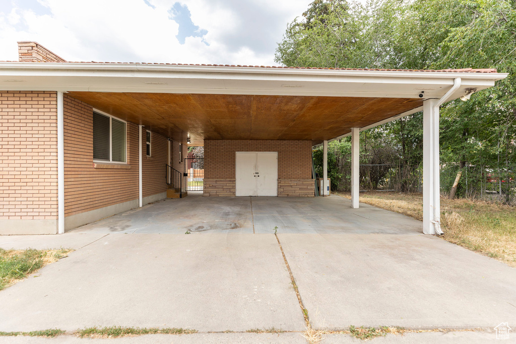 View of parking / parking lot with an attached carport and driveway