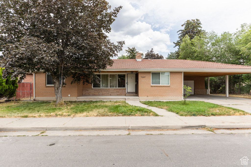 View of front of house featuring brick siding, concrete driveway, a chimney, a tiled roof, and an attached carport