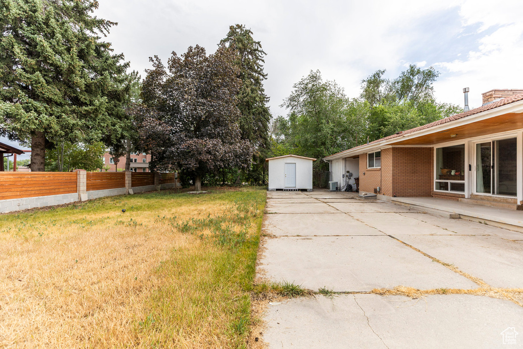 View of yard with a storage unit and a patio