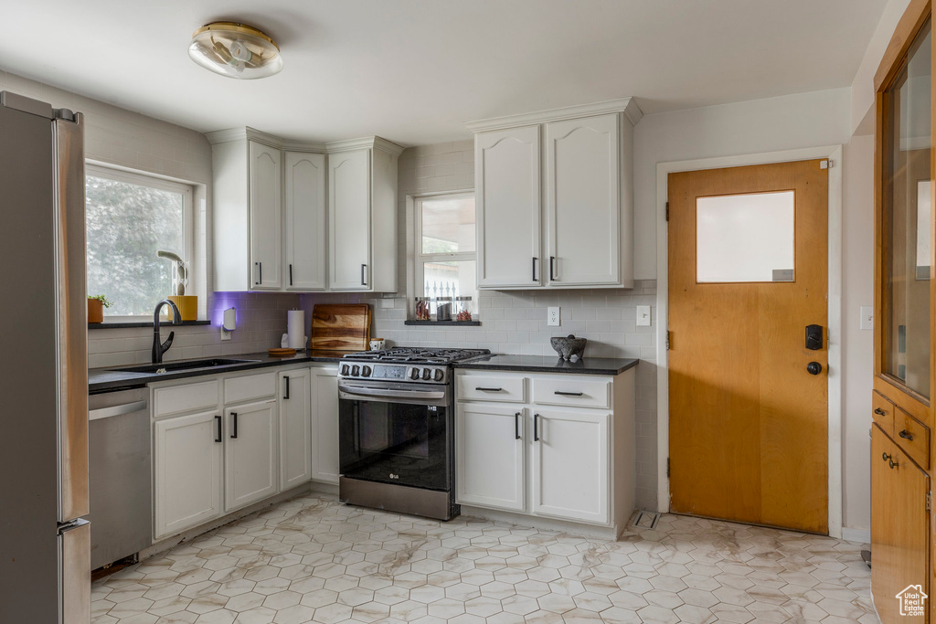 Kitchen with appliances with stainless steel finishes, dark countertops, backsplash, and plenty of natural light