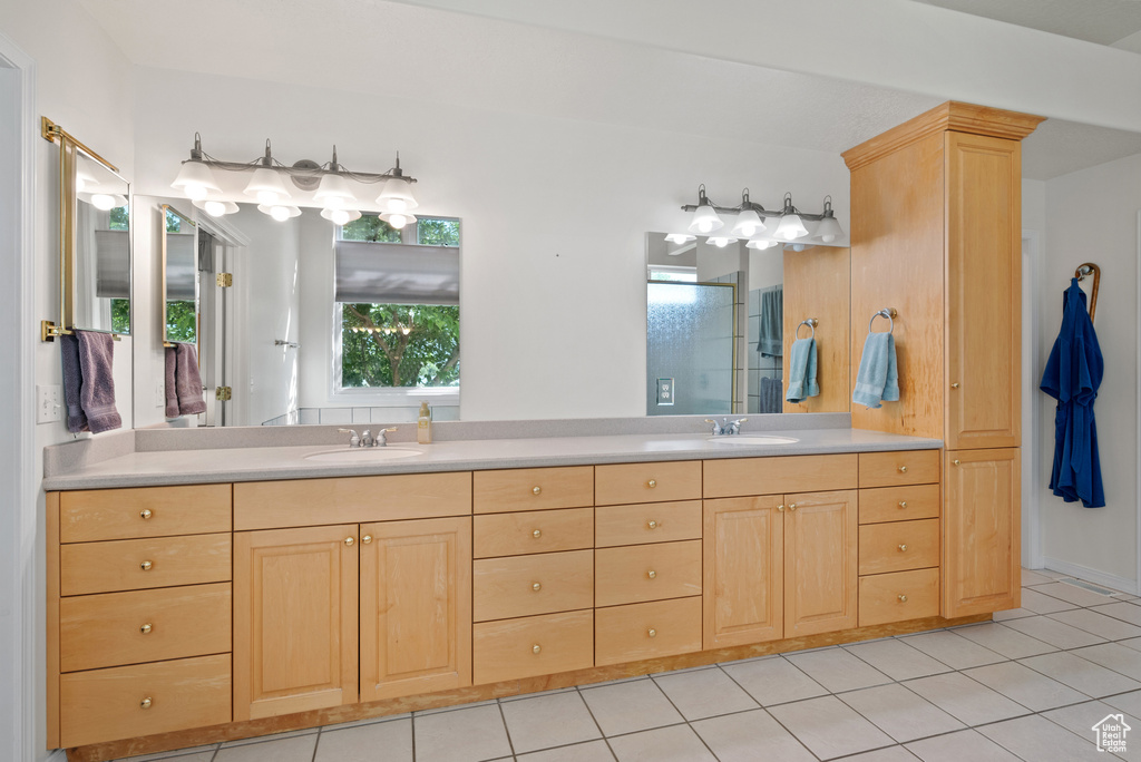 Full bath with double vanity, tile patterned flooring, and a shower