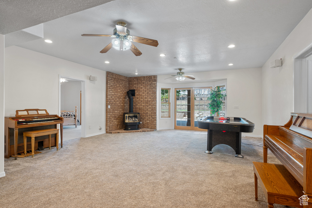 Recreation room featuring a wood stove, recessed lighting, light carpet, and ceiling fan