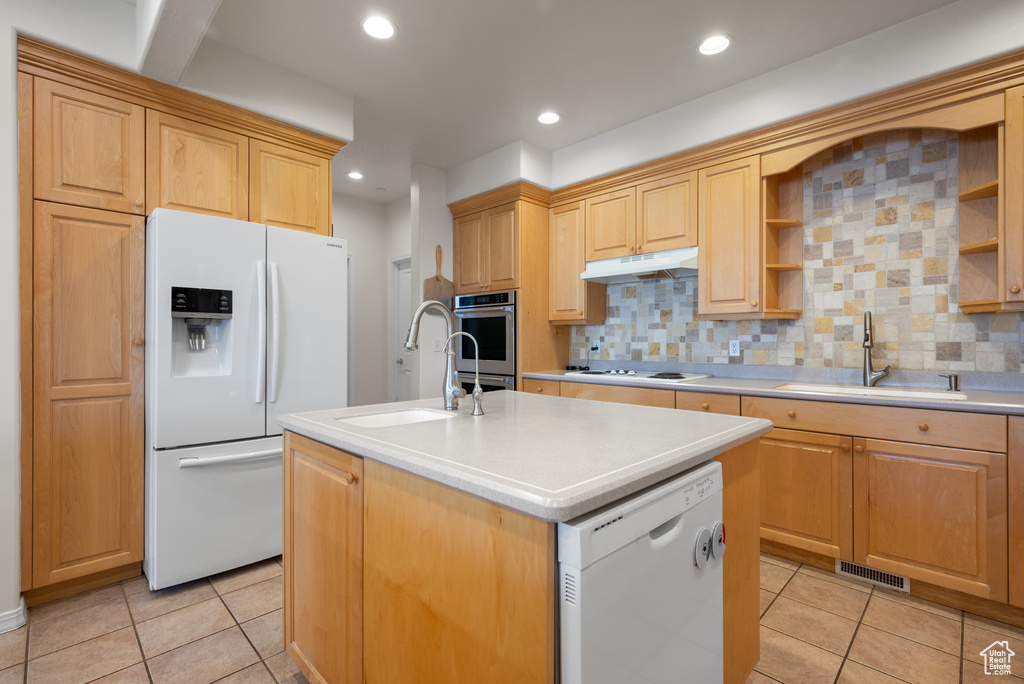 Kitchen featuring white appliances, under cabinet range hood, open shelves, a center island with sink, and light tile patterned flooring