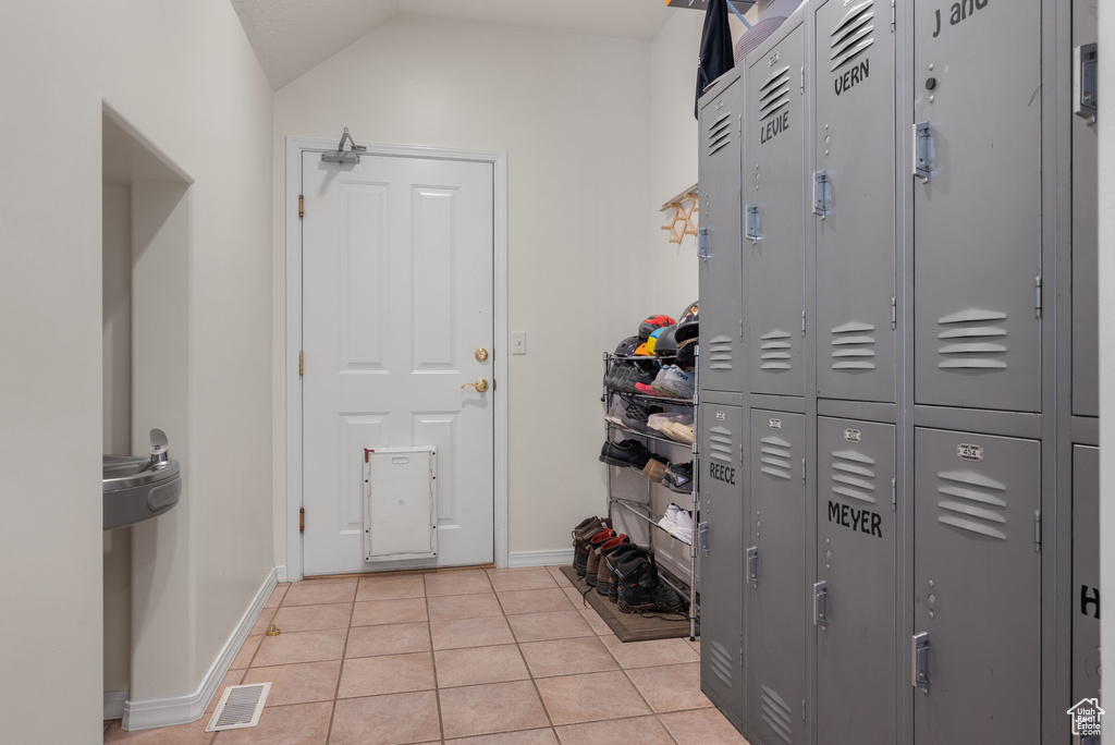 Mudroom featuring light tile patterned floors and vaulted ceiling