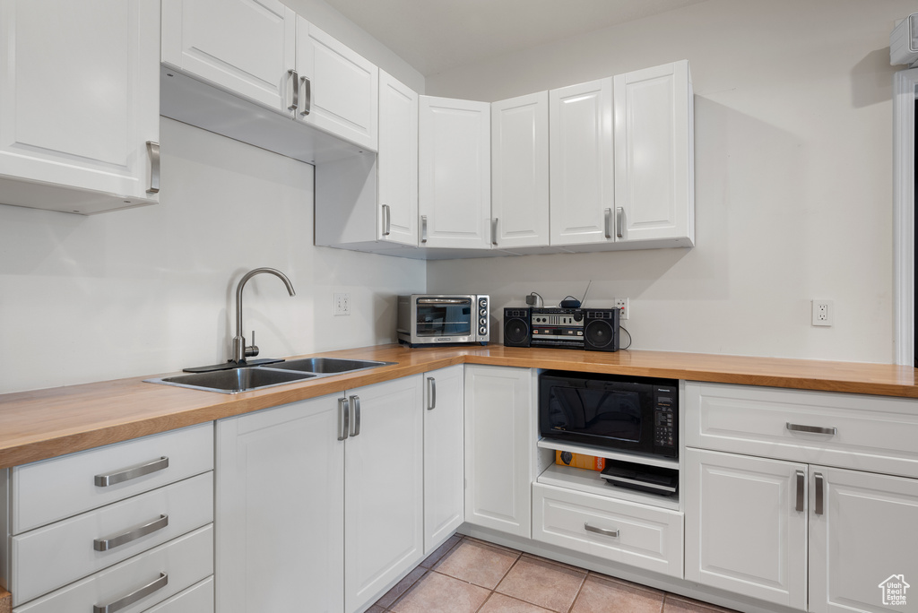 Kitchen with wooden counters, black microwave, and white cabinets