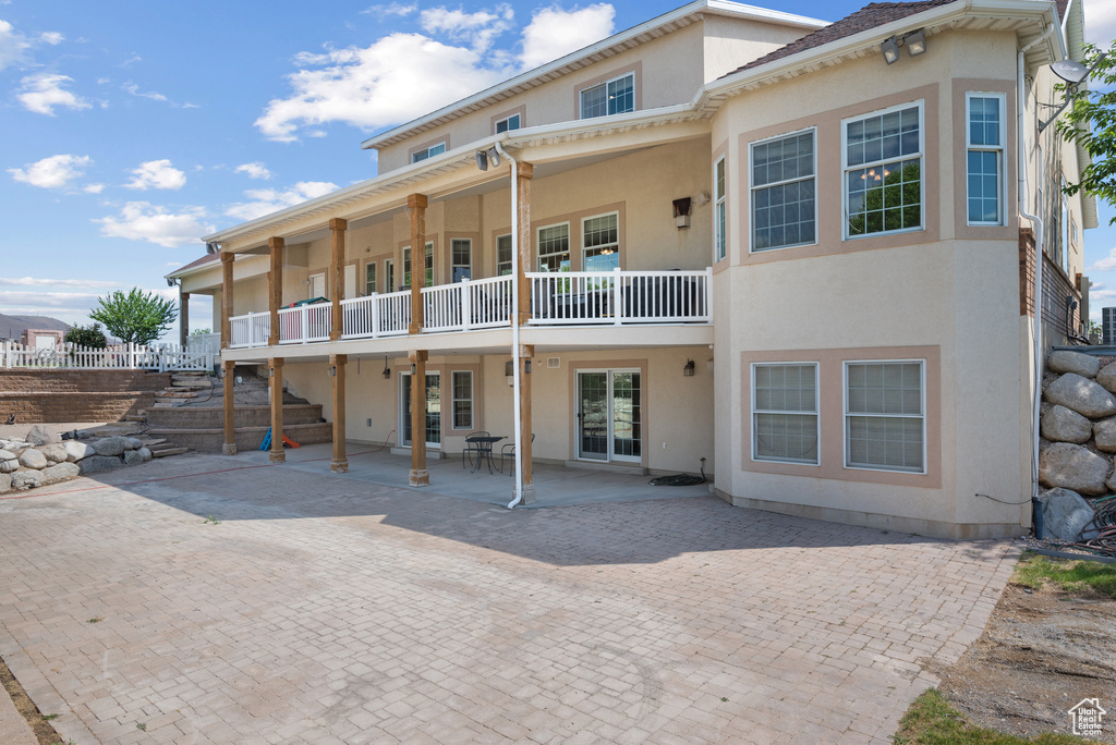 Rear view of house featuring a patio area, stucco siding, french doors, and a balcony
