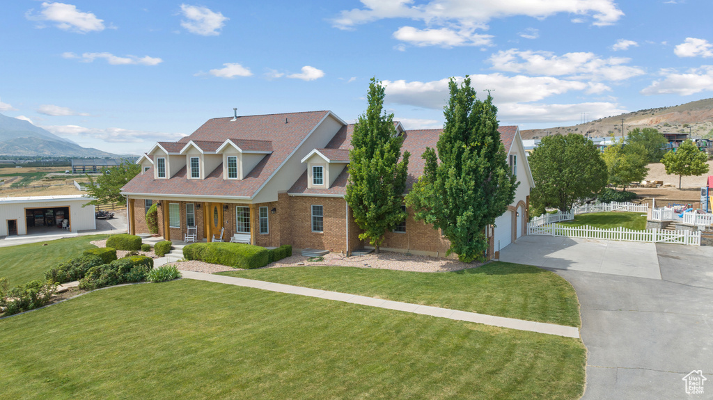 View of front of house with concrete driveway, brick siding, a mountain view, and covered porch