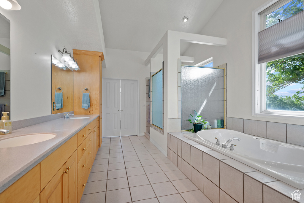 Bathroom with a bath, healthy amount of natural light, a stall shower, and double vanity