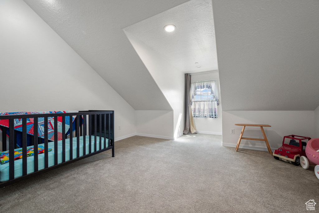 Bedroom with carpet, a textured ceiling, and lofted ceiling