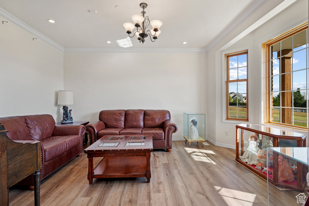 Living room featuring a chandelier, light wood-type flooring, ornamental molding, and recessed lighting