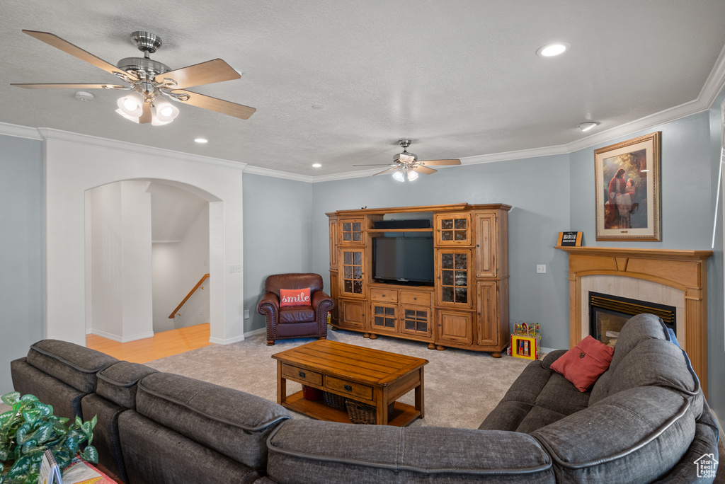 Living area featuring a ceiling fan, arched walkways, crown molding, light carpet, and recessed lighting